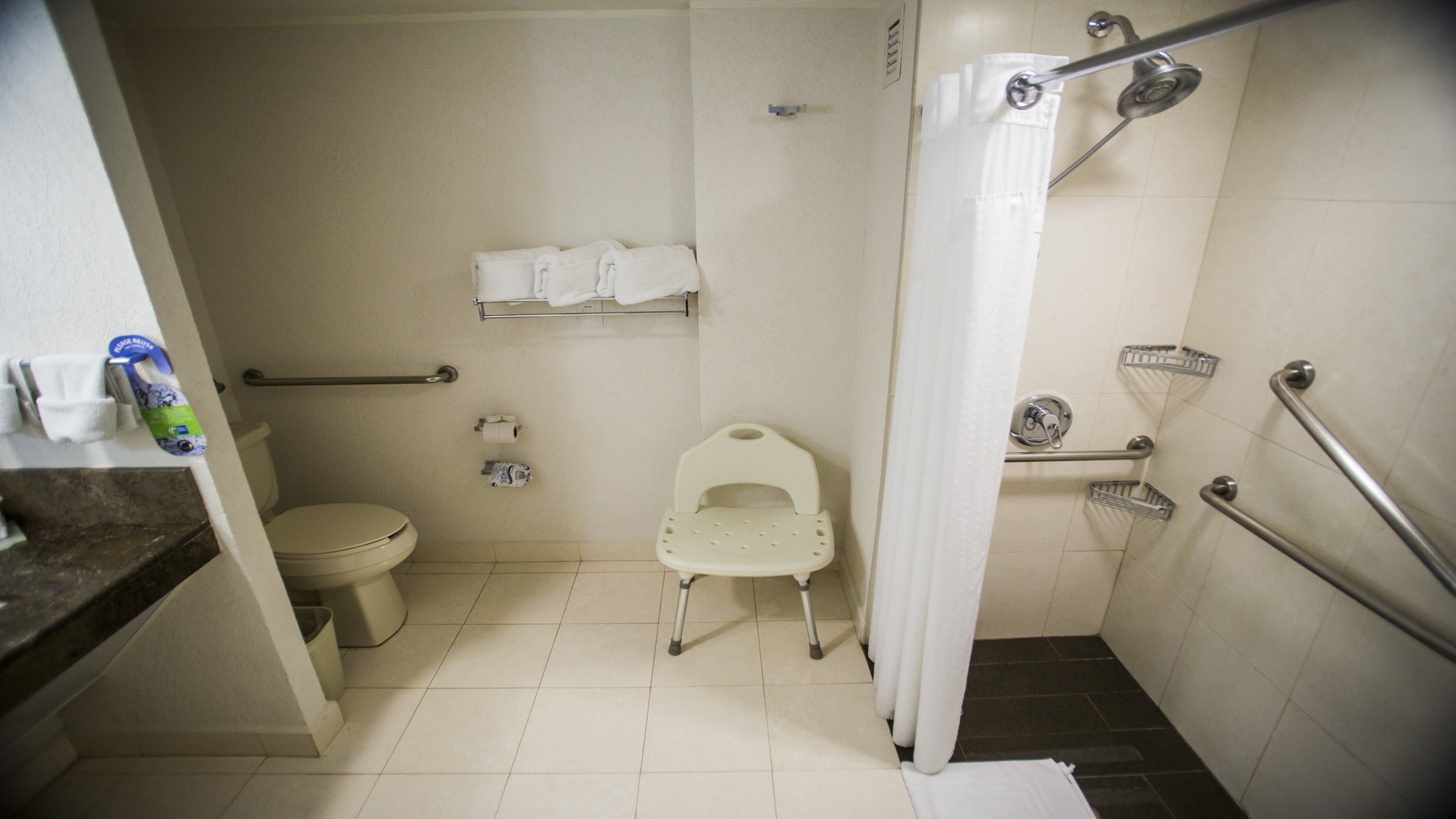 A small, compact bathroom with a toilet, a shower stall, and a grab bar.