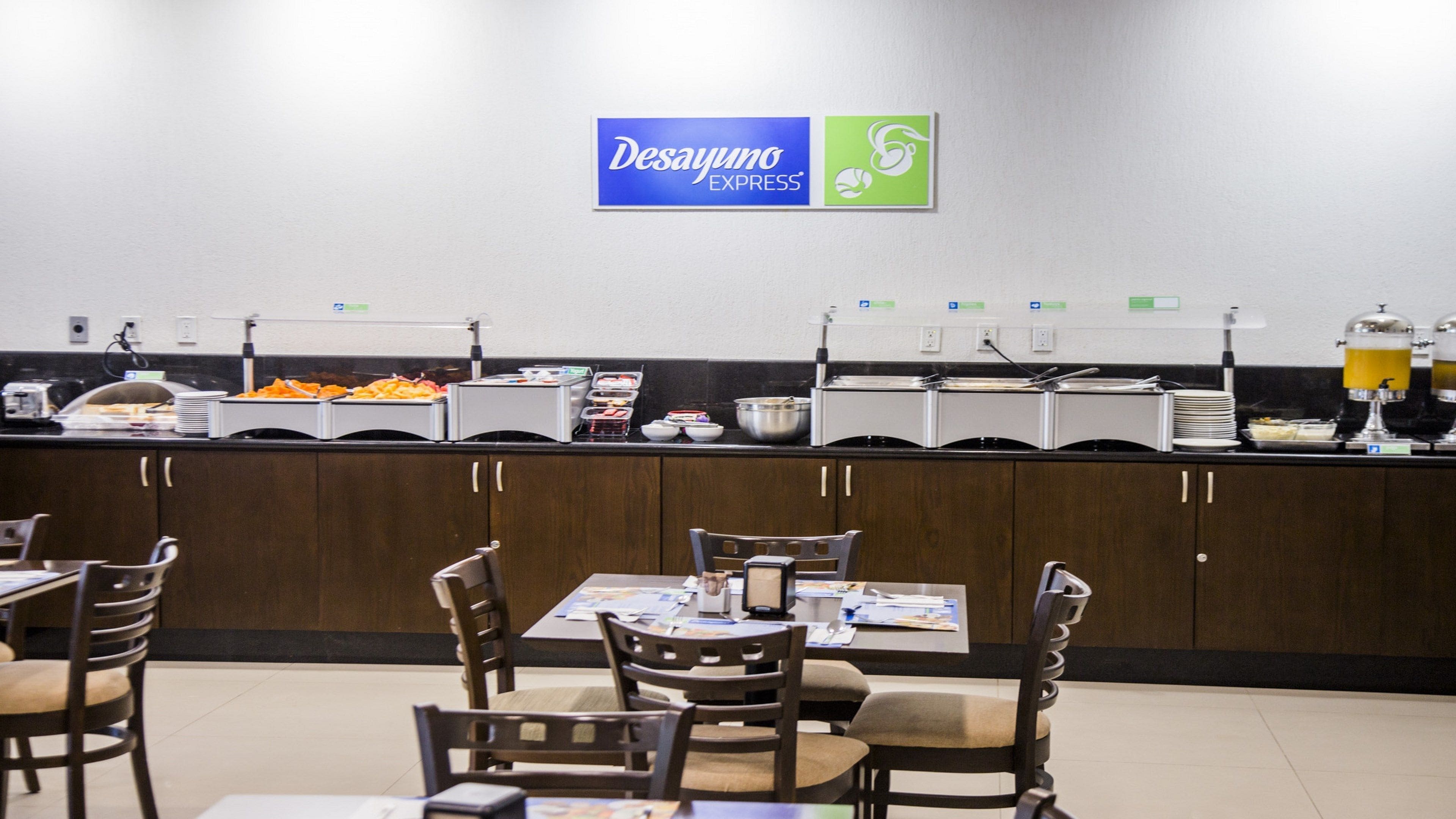 Zona de bufé con distintas estaciones de comida, un cartel que dice Desayuno Express y disposición de mesas.