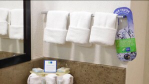 A bathroom with a marble countertop, a mirror, and a towel rack with white towels. There is a soap dispenser and a sign on the countertop. - Holiday Inn Express Tuxtla Gutierrez La Marimba by IHG (Tuxtla Gutierrez)