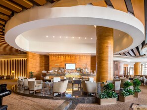 A spacious lobby with a central bar area, multiple seating arrangements, and a grand piano. - Swissotel Living Al Ghurair (Dubai)