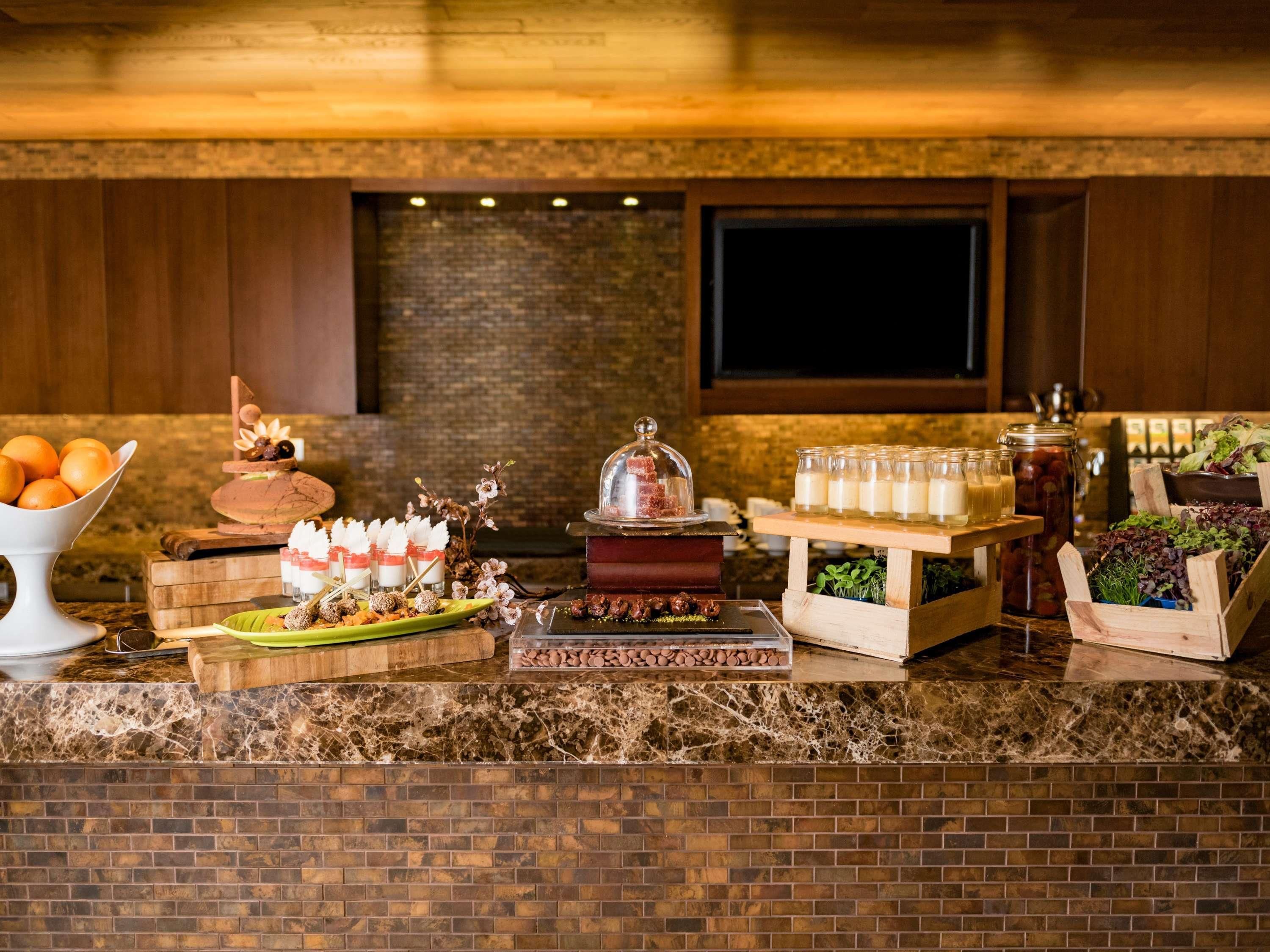 A buffet setup with various food items and a television in the background.