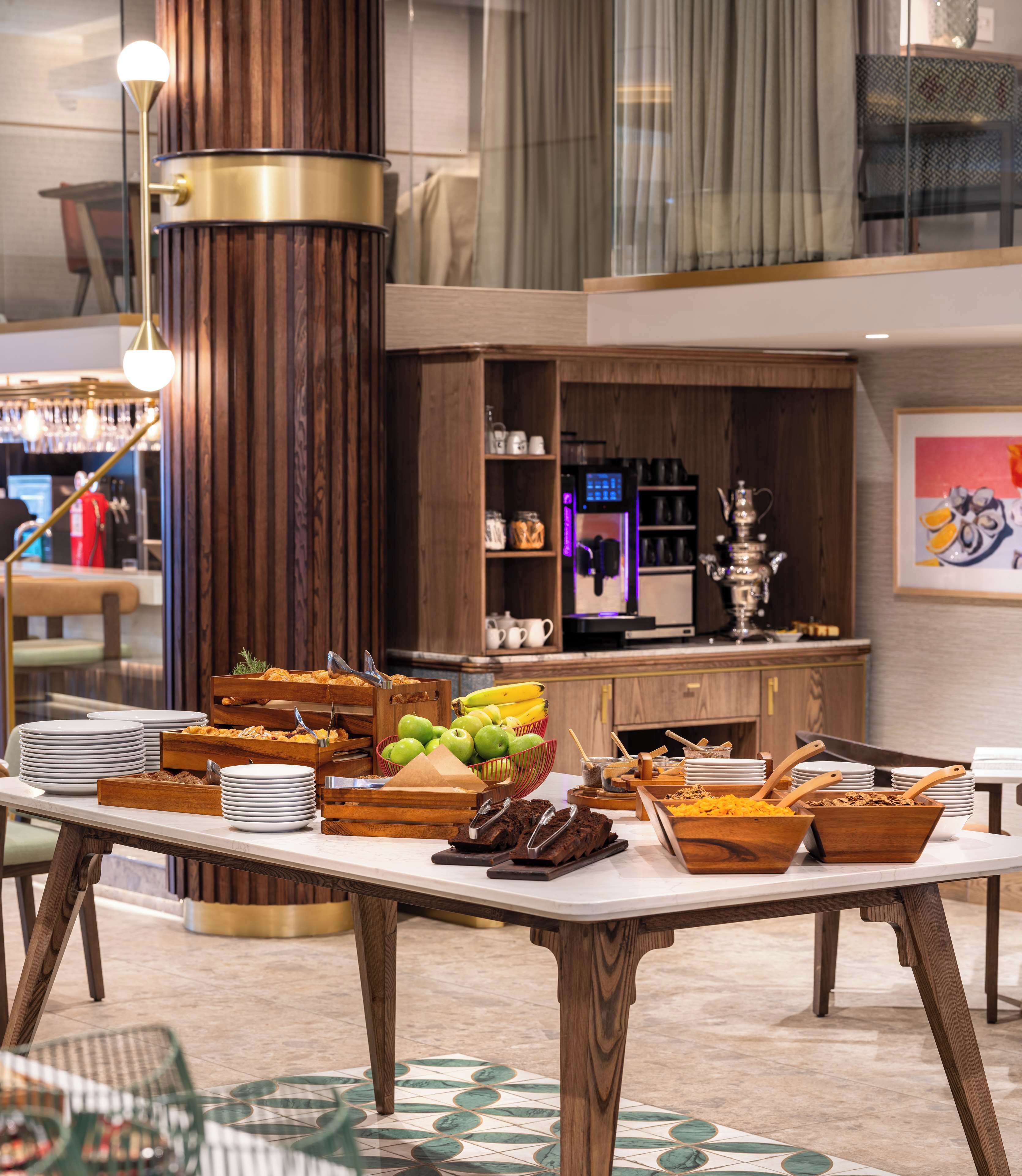 A buffet setup with various food items and a coffee machine in the background.