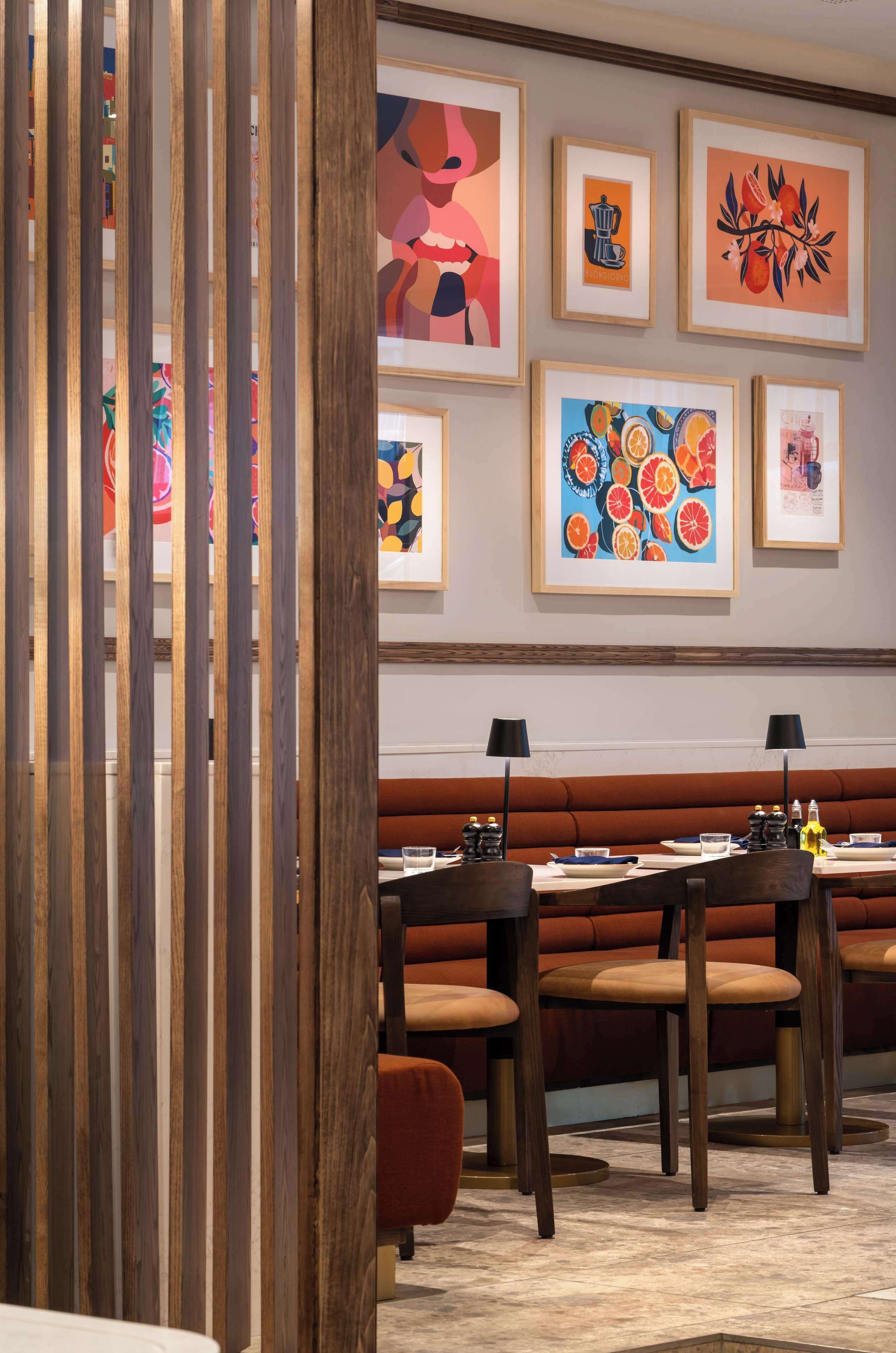 Un ristorante con listelli di legno, una panca imbottita rossa e opere d'arte appese al muro.