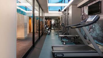 A gym with treadmills, weight machines, and a mirrored wall.