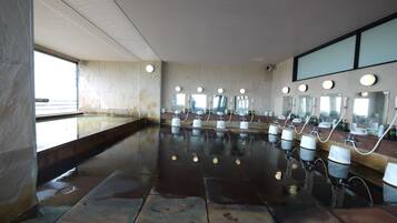 A spacious, modern bathroom with multiple sinks, large mirrors, and a wet floor indicating recent use.