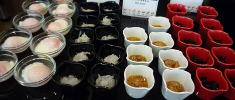 A variety of food items displayed in small bowls, each labeled with different names and prices.