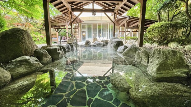 A traditional Japanese onsen with a stone-tiled floor, large rocks, and a wooden pavilion structure. - Route-Inn Grantia Fukuokamiyawaka-wakitaonsen- (Miyawaka)
