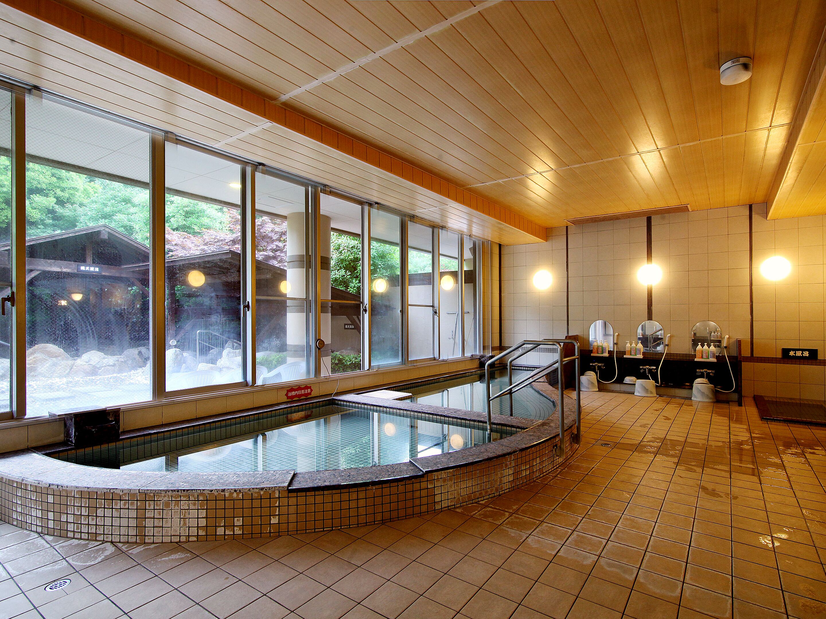 A large indoor swimming pool with a tiled floor and a wooden ceiling.