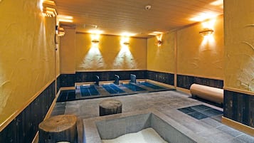 A sauna room with three benches, a stone basin, and wooden accents.