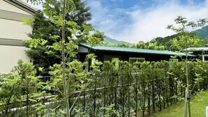 A building with a green roof, surrounded by a variety of trees and a mountainous backdrop. - Route-Inn Grantia Fukuokamiyawaka-wakitaonsen- (Miyawaka)