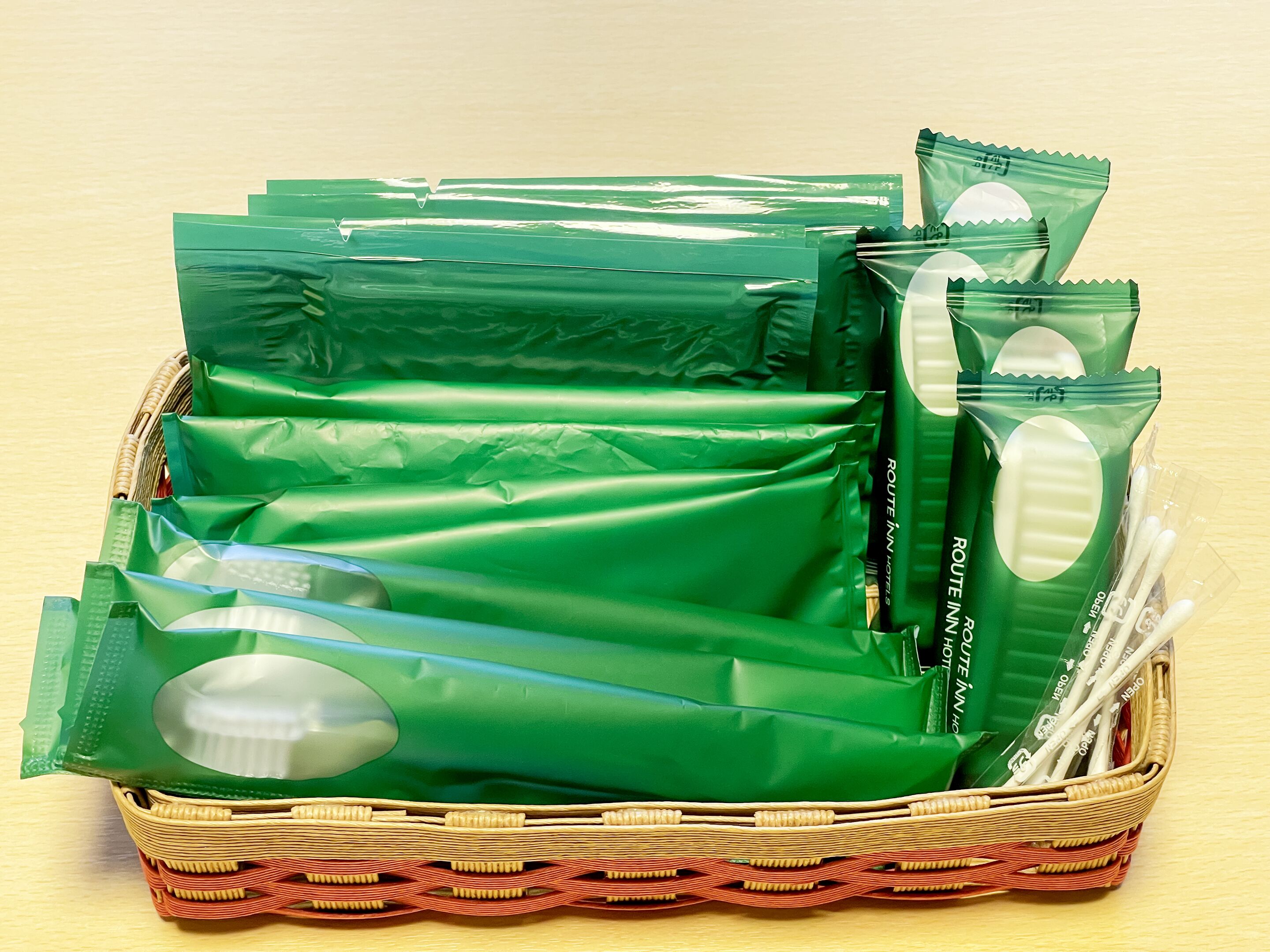 A wicker basket filled with green plastic bags and white toothbrushes.