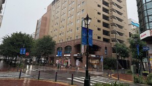 A multi-story hotel with a brick facade, multiple balconies, and a ground-level entrance with signage. - Hotel Route-Inn Yokohama Bashamichi (Yokohama)