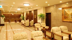 A hotel lobby with a reception desk, seating area, and a large painting on the wall. - Hotel Route-Inn Yokohama Bashamichi (Yokohama)