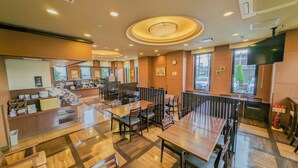 A restaurant with a modern interior, featuring wooden flooring, multiple dining tables, and a buffet area with various food items. - Hotel Route - Inn Towada (Towada)