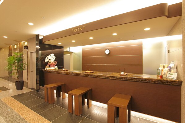 A reception area with a counter, seating, a clock, and a potted plant. - Hotel Route Inn Nagoya Sakae (Nagoya)