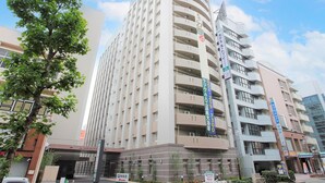 Et højt, moderne hotel med flere etager og altaner, med skilte der angiver faciliteter og tjenester.