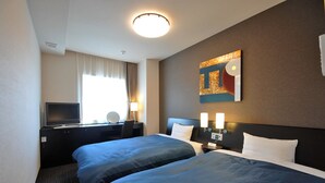 A hotel room with two beds, a desk with a television, a lamp, and a painting on the wall.