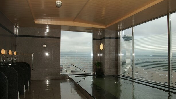 A modern indoor pool area with a view of the sea, equipped with multiple water fountains and a seating area with a railing.