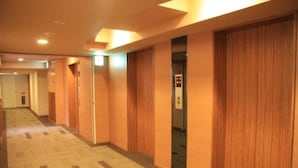 Corredor de hotel com lambris de madeira, piso carpetado e um elevador.