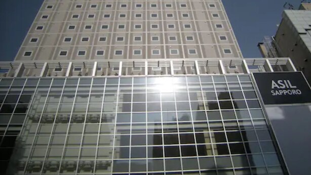 Um edifício alto com uma grade de janelas e uma placa com a inscrição