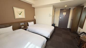 A hotel room with two beds, a bedside table, a lamp, a picture on the wall, and an air conditioning unit.