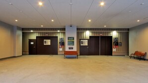 Eine geräumige Lobby mit hoher Decke, zwei Aufzügen und einer Bank.