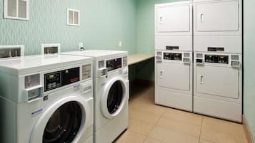 A laundry room with two front-loading washing machines and two stacked dryers.