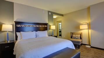 Una habitación de hotel con una cama grande, dos mesitas de noche con lámparas, una silla y una pequeña mesa.