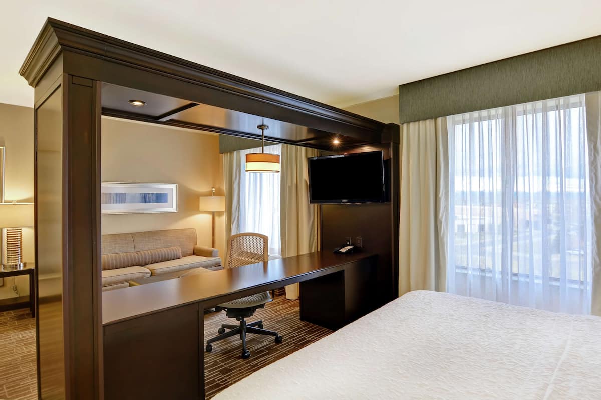A hotel room with a bed, a desk with a chair, a TV, and a sofa.