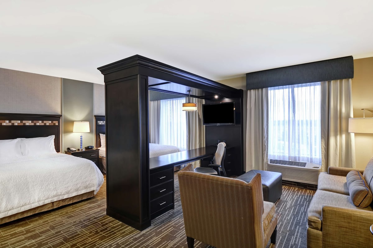 A hotel room with a bed, a desk with a chair, a sofa, and a TV.