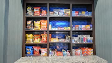 A snack and beverage display in a hotel room with various brands of chips, snacks, and bottled drinks.