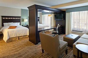 A hotel room with a large bed, a desk, a chair, and a sofa. - Hampton Inn & Suites- Denver/Airport-Gateway Park (Denver)