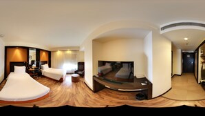 Una habitación de hotel moderna con una cama curvada, un televisor de pantalla plana, un escritorio y una zona de estar.