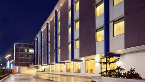 Un hotel moderno con fachada curva, varios pisos y ventanas iluminadas.