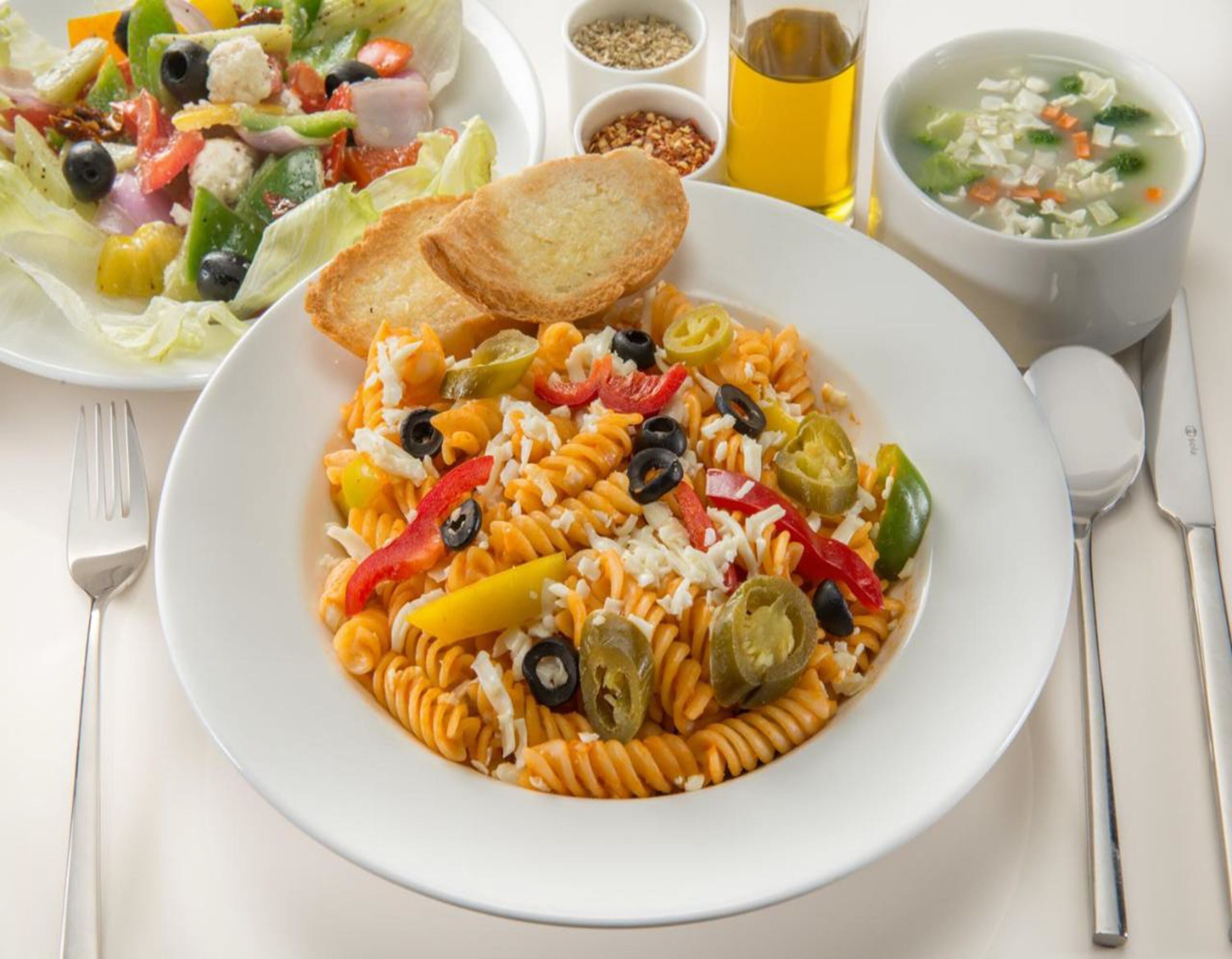 Eine Pasta-Zubereitung mit Gemüse und Käse, eine Suppe und ein Beilagensalat.