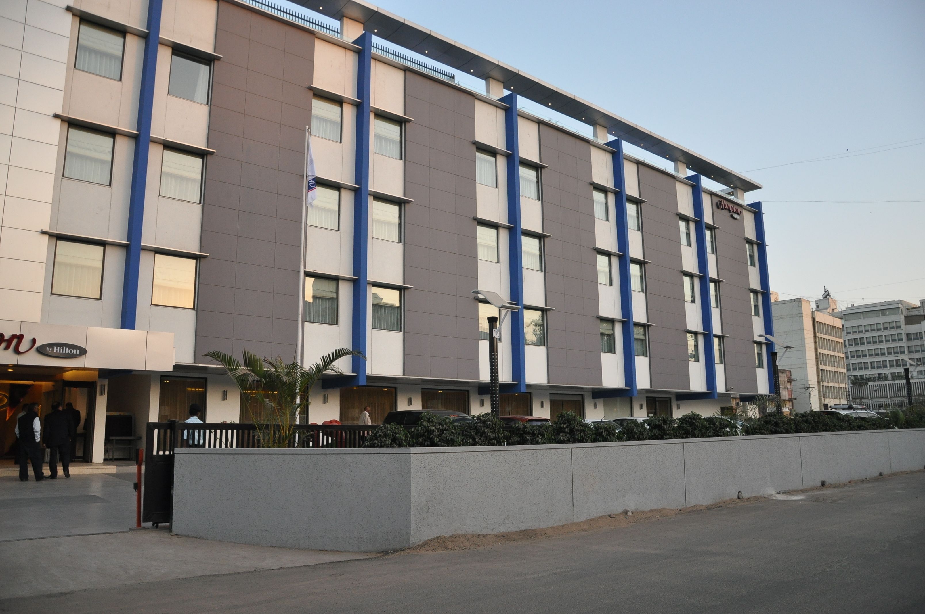 Un hotel de varios pisos con fachada moderna, que destaca por una paleta de colores azul y beige.