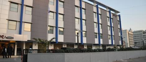 Un hotel de varios pisos con fachada moderna, que destaca por una paleta de colores azul y beige.