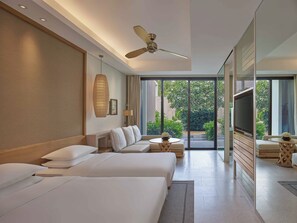 Ein modernes Hotelzimmer mit einem großen Bett, einer Sitzecke, einem Fernseher und einem Deckenventilator.