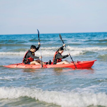 Two people in a red kayak on the ocean.