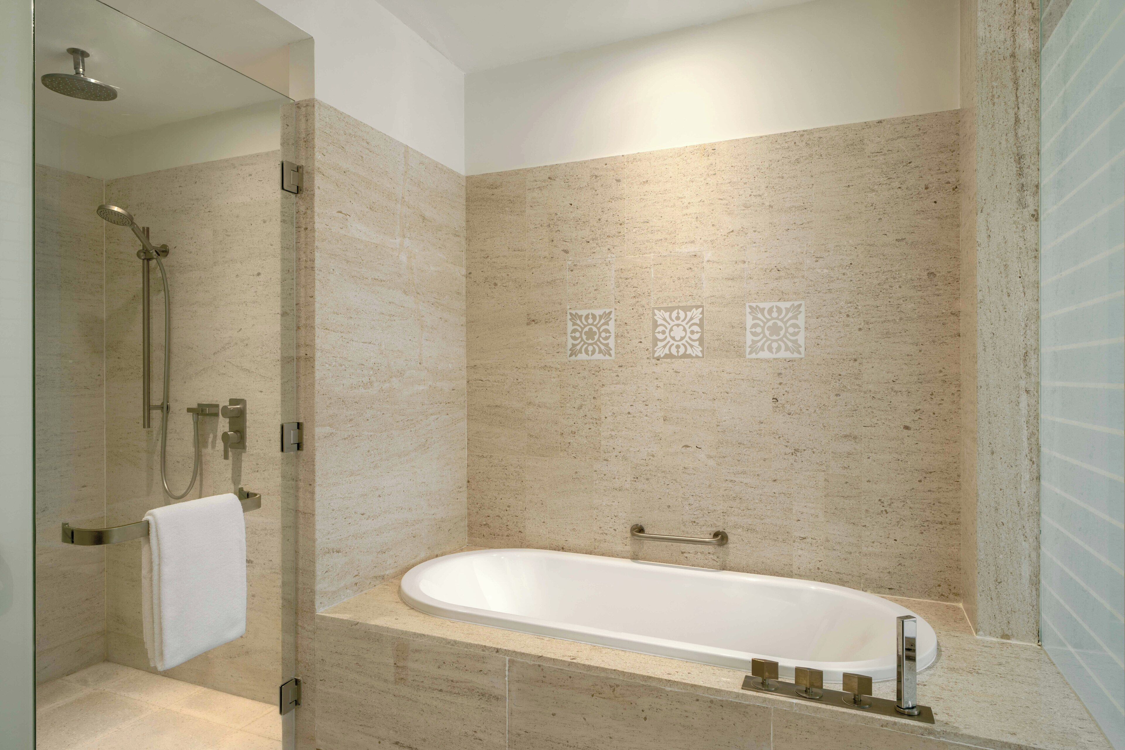 A modern bathroom with a freestanding bathtub, a glass-enclosed shower, and decorative wall tiles.