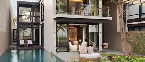 A modern house with a swimming pool, outdoor seating, and a balcony.
