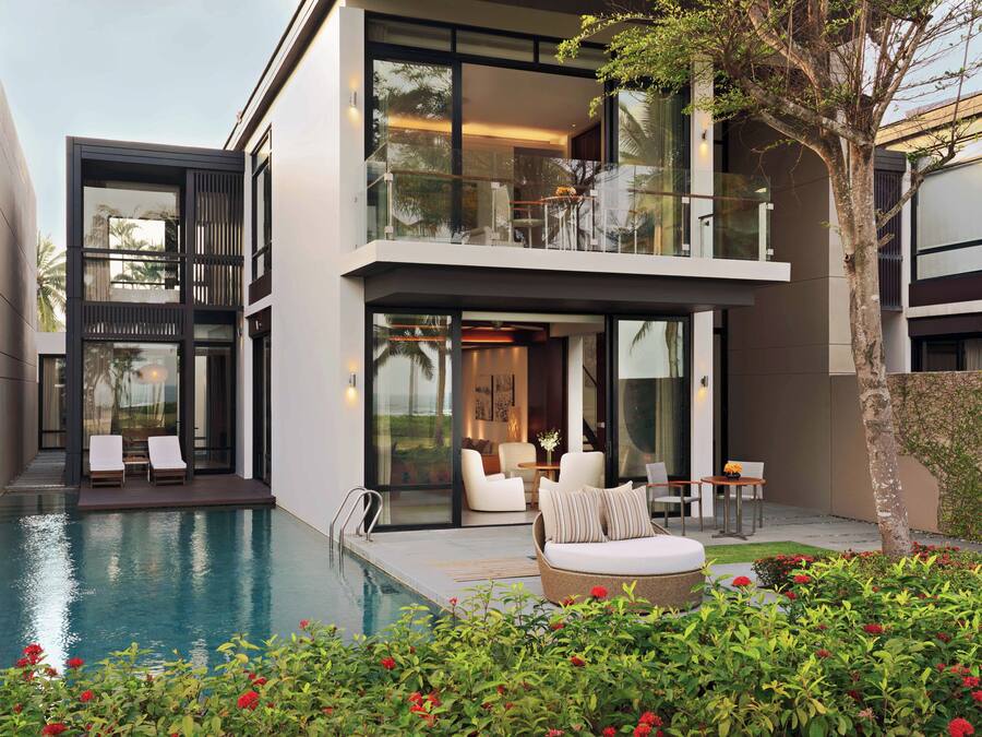 Et moderne hus med swimmingpool, udendørs møbler og en balkon.