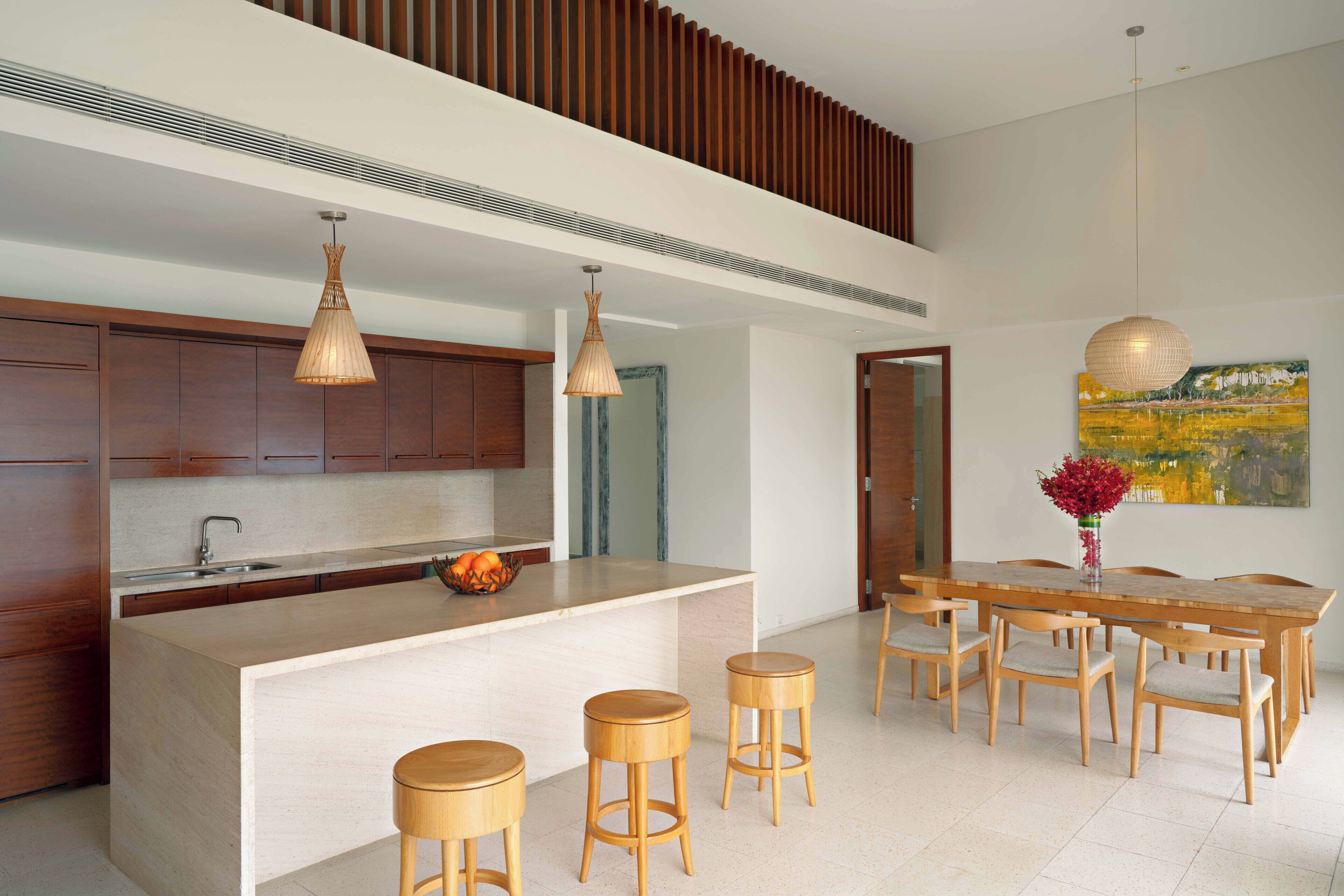 Una cocina moderna con armarios de madera, una isla central con taburetes e iluminación colgante.