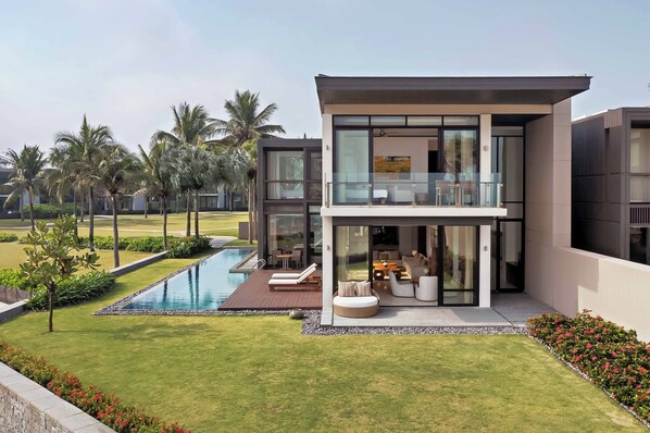 Una casa moderna con piscina, mobiliario exterior y un jardín bien cuidado.