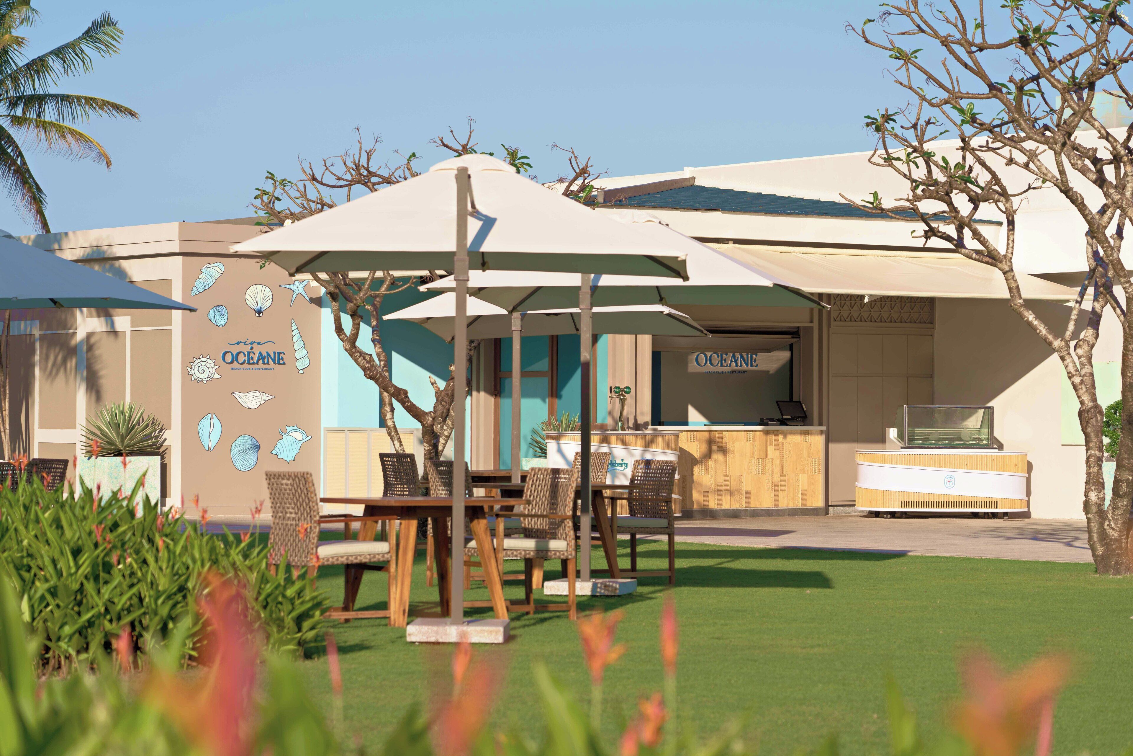 Un restaurante con terraza, barra y una pared decorada con ilustraciones de temática marina.