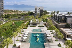 Ein Resort mit zentralem Schwimmbad, Palmen und Blick auf den Ozean.