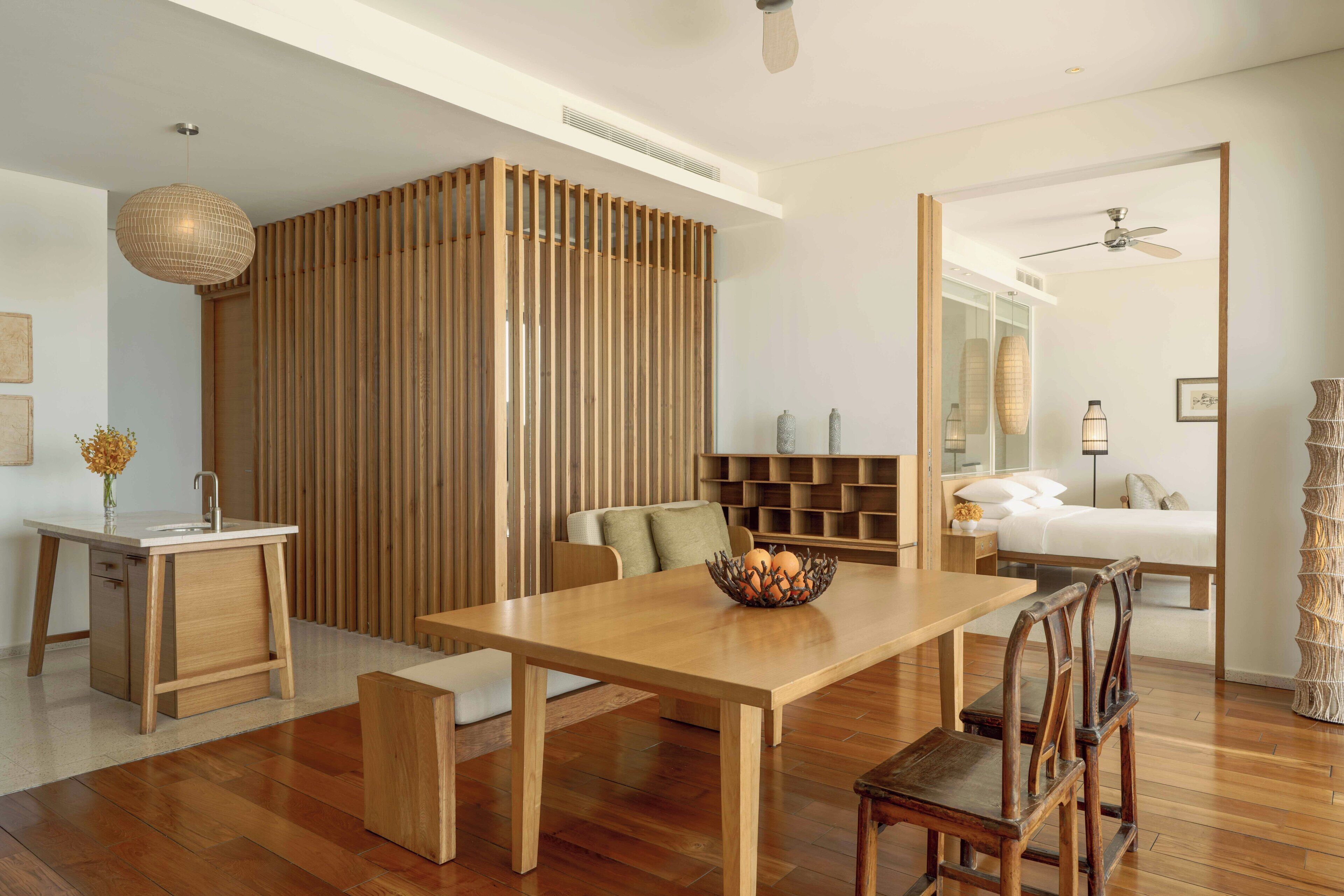 Uma sala de estar moderna com uma mesa de jantar de madeira, cadeiras, um sofá e um painel decorativo na parede.