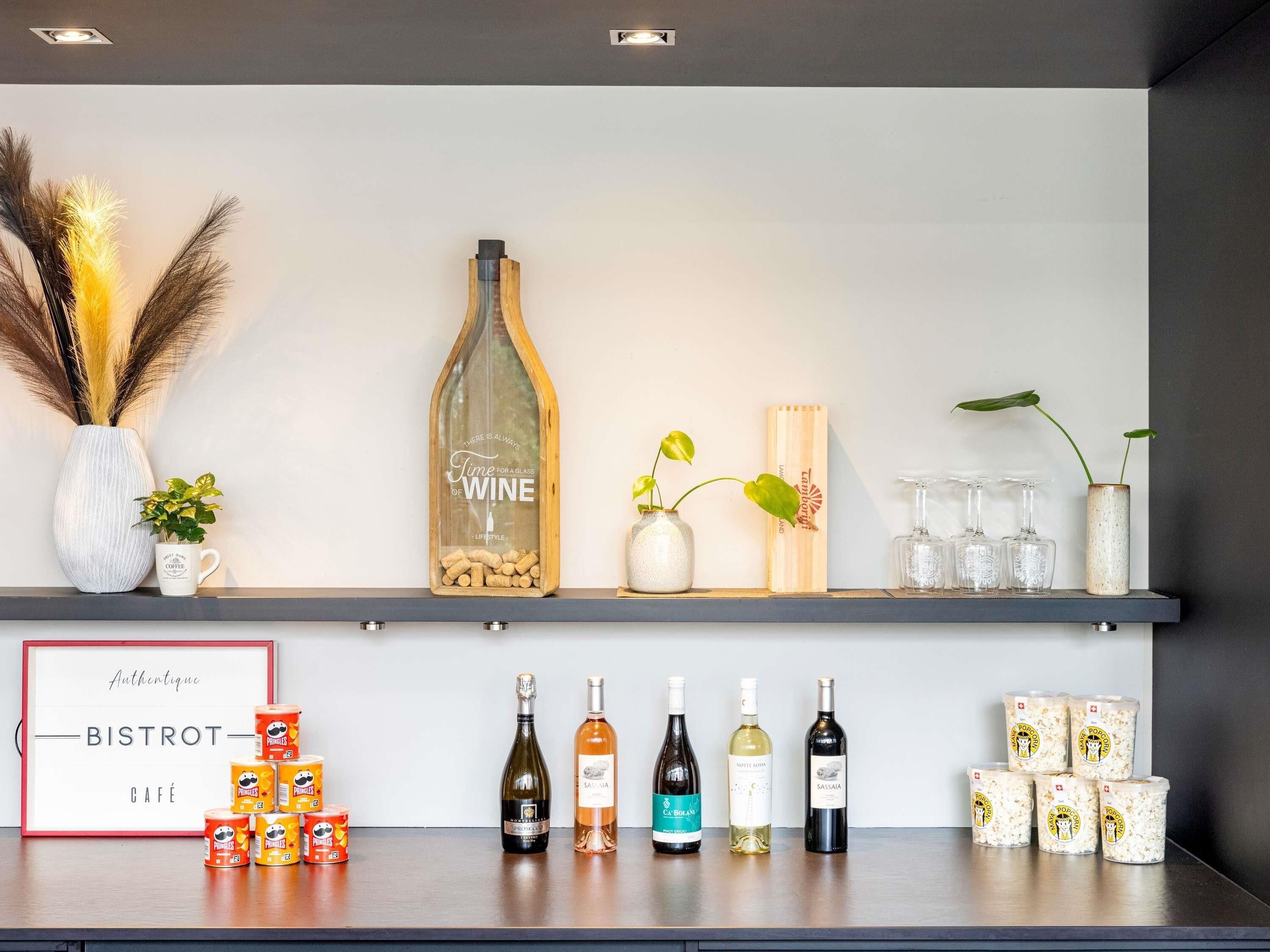 A bar area with a wine bottle, glasses, and snacks.