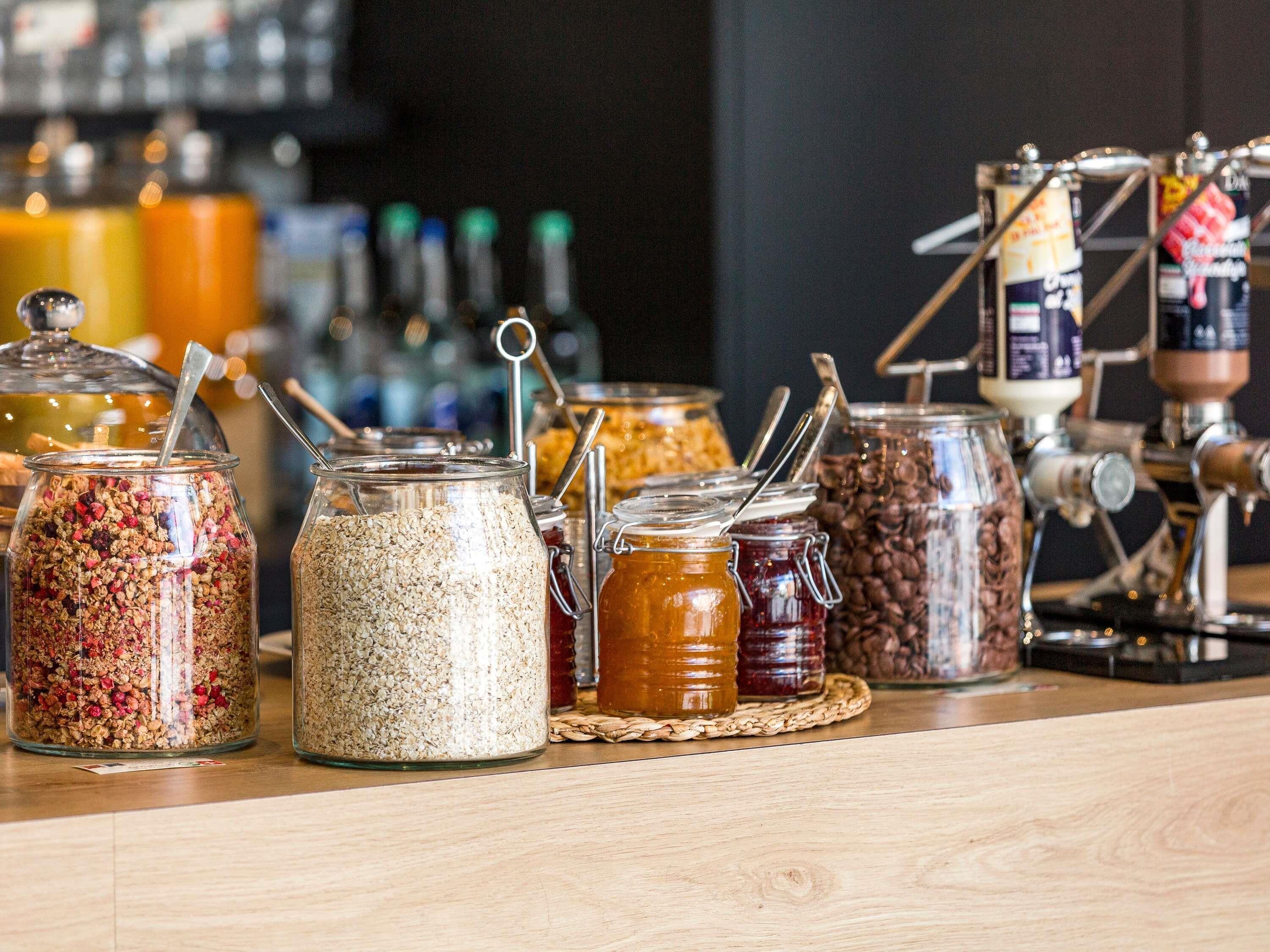 A variety of food items in jars on a counter, with a coffee machine in the background.