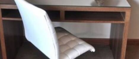 A room with a wooden desk, a white chair, and two framed pictures on the wall.